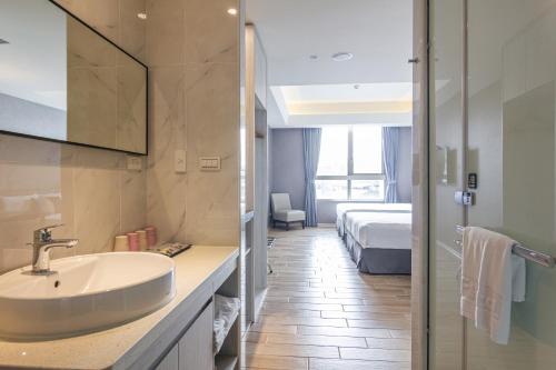 a bathroom with a sink and a bed in a room at CHECK inn New Taipei LuZhou in Taipei