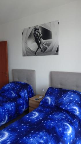 a bedroom with two beds with blue sheets and a picture at La Casa di Tato in Montecarotto