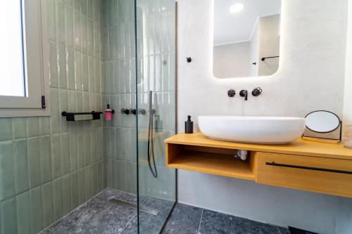 a bathroom with a sink and a glass shower at Iaspis Luxury Suites in Bendevís