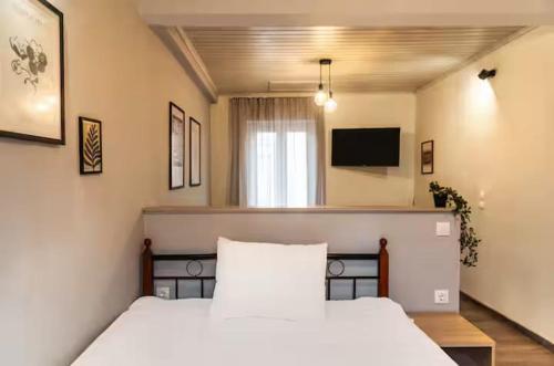 a bedroom with a white bed and a television at Burnelia Vacation Maisonette in Lefkímmi