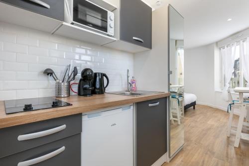 une cuisine avec des placards gris et un comptoir dans l'établissement Notre Dame de Rumengol, à Brest