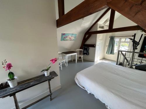 a bedroom with a large bed and a table at Het Koetshuis in Gouda