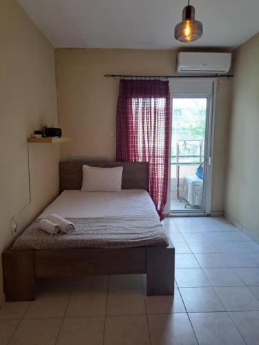 a bed in a room with a window and a door at Cozy and quiet apartment at the center of the city in Komotini