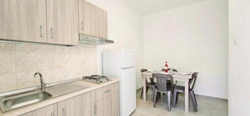 a kitchen with a table and a white refrigerator at Agriturismo Le Ville con Piscina idromassaggio, Capo Vaticano in Ricadi