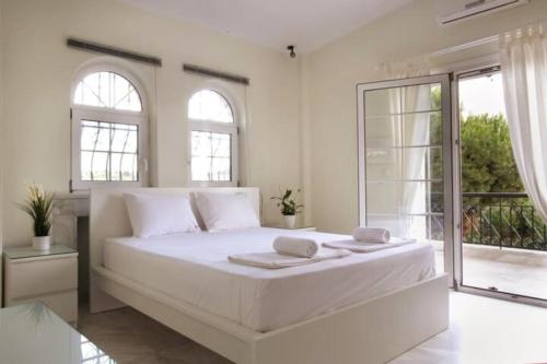 a white bedroom with a large bed with two windows at Stone Villa Nea Potidaia in Nea Potidaea