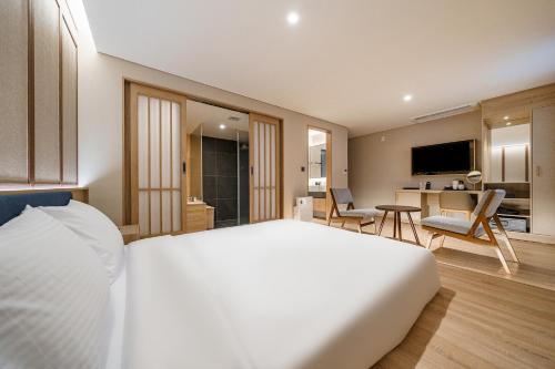 a bedroom with a white bed and a living room at Hotel Foret The Spa in Busan