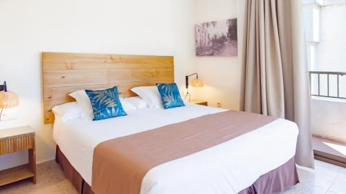 a bedroom with a large white bed with blue pillows at Hotel Eden Mar in Guardamar del Segura