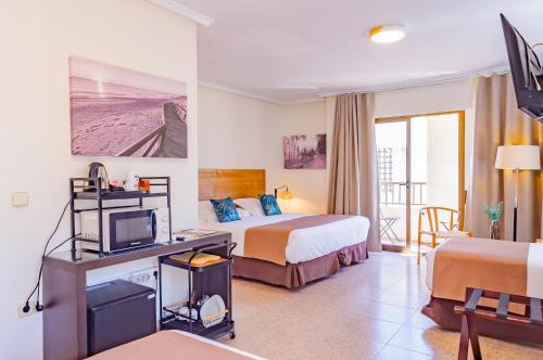 a hotel room with two beds and a television at Hotel Eden Mar in Guardamar del Segura