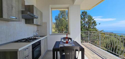 a kitchen with a table and a balcony with a view at Agriturismo Le Ville con Piscina idromassaggio, Capo Vaticano in Ricadi