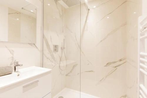 une salle de bain blanche avec une douche et un lavabo dans l'établissement Cannes Vue Mer, Piscine, Plage, à Cannes