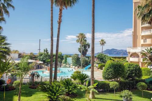 une vue sur la piscine d'un complexe hôtelier avec des palmiers dans l'établissement Cannes Vue Mer, Piscine, Plage, à Cannes