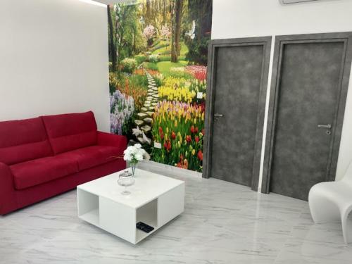 a living room with a red couch and a painting of flowers at Ermioni Apartments in Limassol