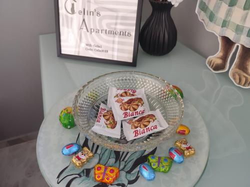 a glass table with a plate of food and candy at Celin's Appartment in Tríkala
