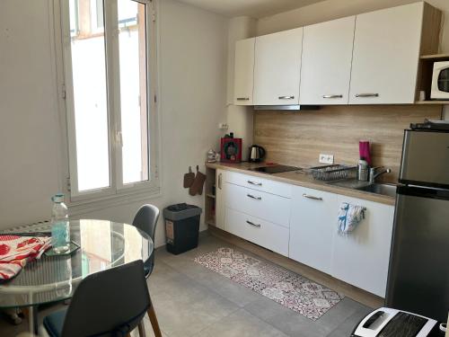 une cuisine avec des armoires blanches, une table et une fenêtre dans l'établissement Charmant T1 à Antibes, à Antibes