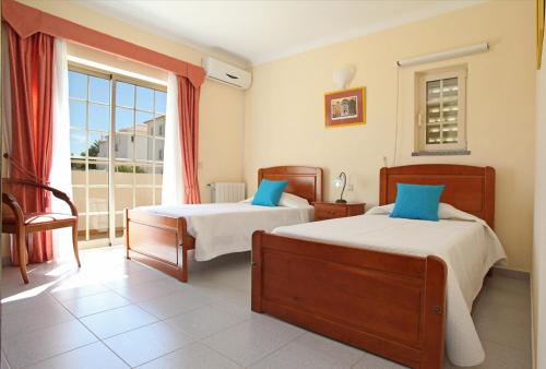 a bedroom with two beds and a large window at Villa Naomi - Large garden and terrace in Albufeira