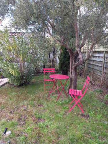 - une table de pique-nique rouge et des chaises dans la cour dans l'établissement Maison familiale entourée de verdure près d'Arcachon, plages et Golfs, à Gujan-Mestras