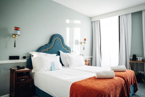 a bedroom with a large white bed with an orange blanket at GRANDE HOTEL PARIS by STAY HOTELS in Porto