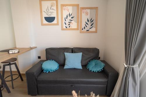 a black couch with blue pillows in a living room at Ocean-Πολυτελές διαμέρισμα στο Αγρίνιο in Agrinion