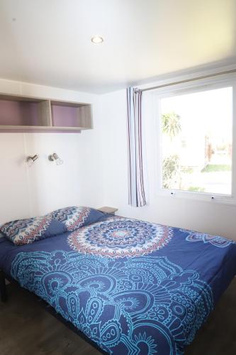 une chambre avec un lit avec une couette bleue et une fenêtre dans l'établissement Cozy Cocon, à Argelès-sur-Mer