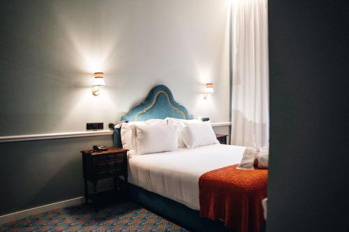 a bedroom with a bed with a blue headboard at GRANDE HOTEL PARIS by STAY HOTELS in Porto