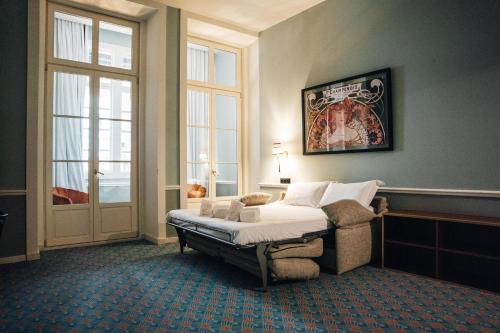a bedroom with a bed and a chair and windows at GRANDE HOTEL PARIS by STAY HOTELS in Porto