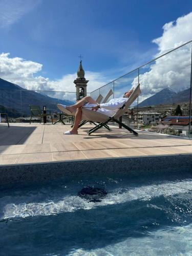 a woman sitting in a chair next to a swimming pool at Wine Hotel Ristorante San Carlo - Boutique Hotel & SPA in Chiuro