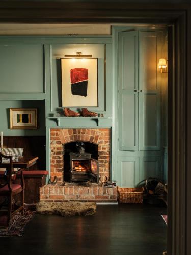 a living room with a brick fireplace with a painting at The Grosvenor Arms in Hindon