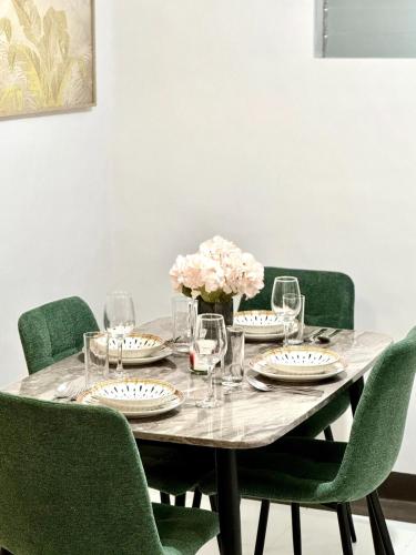 a table with green chairs and a table with glasses and flowers at Cozy 3BR Bungalow House with Netflix & Games in Davao City