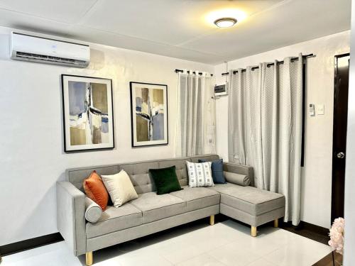 a living room with a couch with pillows on it at Cozy 3BR Bungalow House with Netflix & Games in Davao City