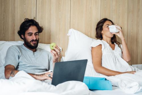 a man and a woman sitting in bed with a laptop at Stay Hotel Lisboa Aeroporto in Lisbon