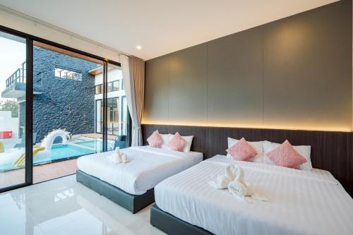 two beds in a room with a swimming pool at Black Rocher Poolvilla Huahin in Hua Hin