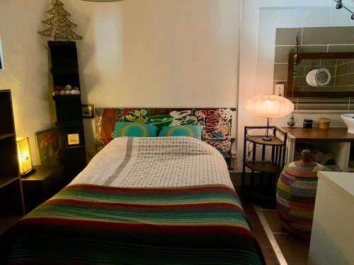 une chambre avec un grand lit avec une couverture colorée dans l'établissement Appart Central à Sète avec balcon, à Sète