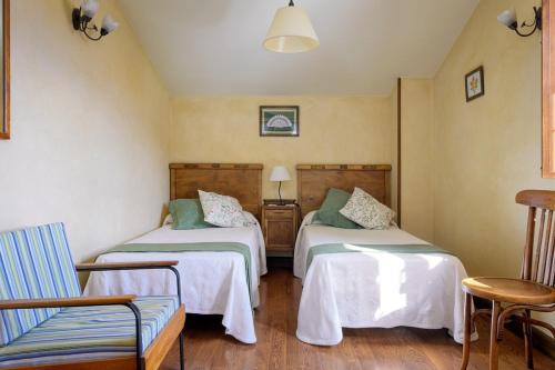 a room with two beds and a chair at Las Fuentes de Mena - Escape in Nature in Lezana de Mena