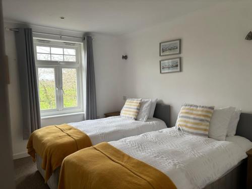 zwei Betten in einem Zimmer mit Fenster in der Unterkunft Cornwall Lodge sleeps 8 full Holiday Park Access in Saint Columb Road Station
