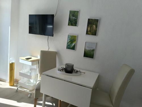 Pokój z białym biurkiem i telewizorem na ścianie w obiekcie Laubgeflüster Entspannung pur mit Sonnenterrasse und optionalem Wellnessraum w mieście Dornum