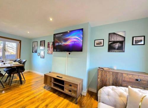 a living room with a couch and a tv on the wall at Super luxury 2 bedroom, full house sleep 5 with garden & parking close to airport in Elderslie