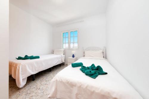 Dos camas en una habitación blanca con arcos verdes. en MarySol 5 terrace with sea views, close to the sea, en Punta Mujeres