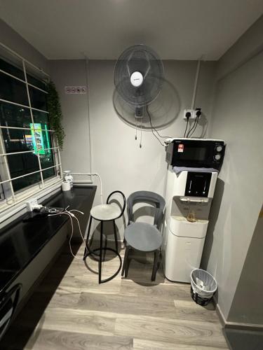 a kitchen with two chairs and a refrigerator and a fan at SS Grey House in Kuala Lumpur
