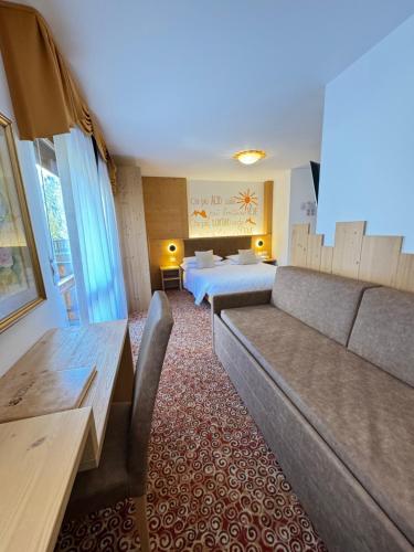 a living room with a couch and a bed at Hotel Europa in San Martino di Castrozza