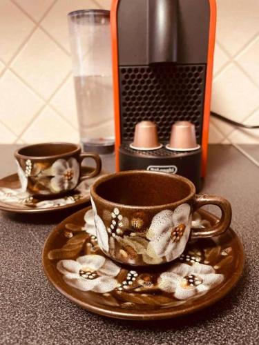 two cups on a plate next to a coffee maker at GreenPark Garden Villa Family Apartments Near Tokaj in Szerencs
