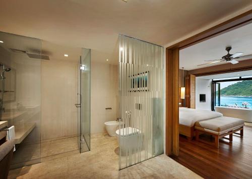 a bathroom with a shower and a bedroom with a bed at The Taaras Beach & Spa Resort in Redang Island