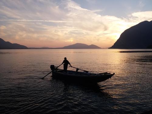 a man rowing a boat in the water at sunset at Hotel Bellavista Meublè in Monte Isola