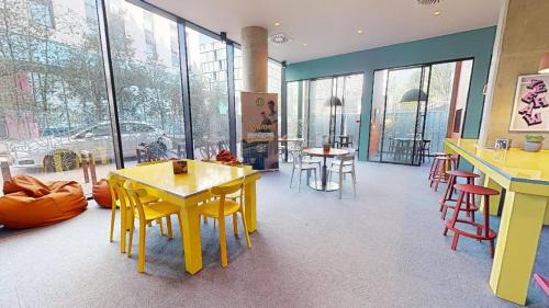 a restaurant with yellow tables and chairs and windows at For Students Only at iQ Brighton in Brighton & Hove