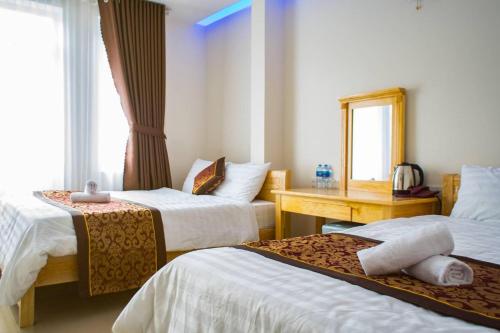 a hotel room with two beds and a mirror at THANH 2 Dalat in Da Lat