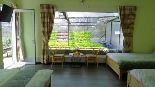 ein Zimmer mit zwei Betten und einem Tisch und einem Fenster in der Unterkunft Vườn Nhà Đan Homestay in Da Lat