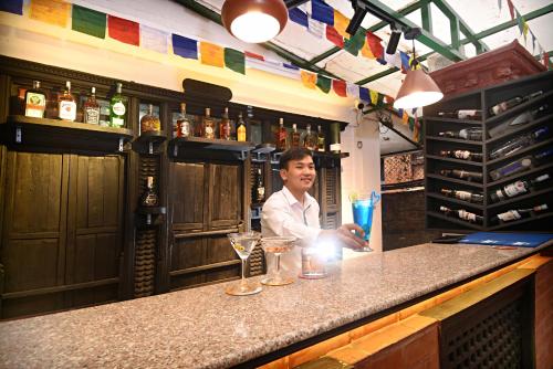 a man sitting at a bar with drinks at Tibet Boutique Hotel in Kathmandu