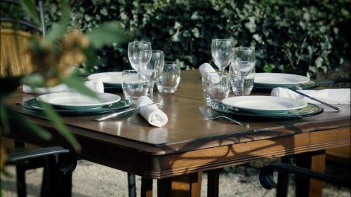 drewniany stół z płytami i kieliszkami do wina w obiekcie Hôtel restaurant Clos des Sullys w mieście Montclus