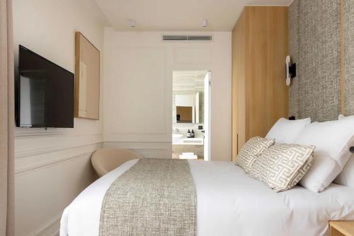 une chambre avec un lit blanc et une télévision dans l'établissement Splendid Apartment 2BR 6P Near Palais Royal, à Paris