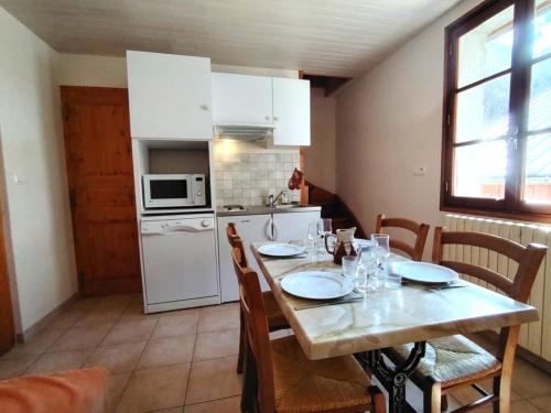 cocina con mesa de madera con sillas y cocina con electrodomésticos blancos en Les Oulles 19, en La Chapelle-en-Valgodemard