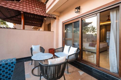 a balcony with chairs and a table and a bedroom at Ananta Spa & Resort Jaipur in Jaipur
